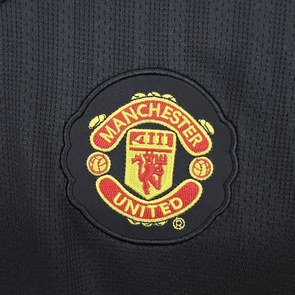 Retro away football jersey Manchester United crest patch on textured black fabric