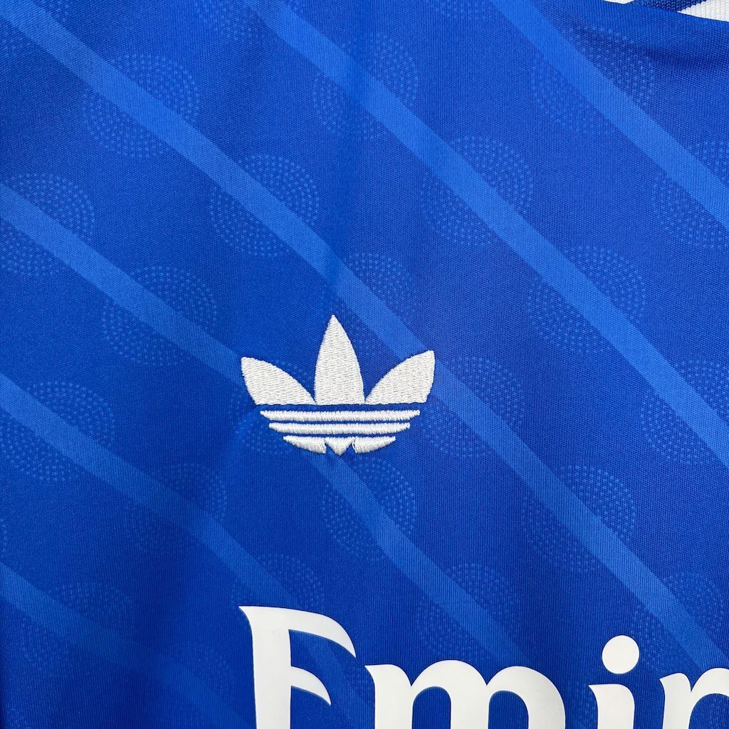 Real Madrid jersey adidas trefoil logo on blue fabric, with subtle pattern