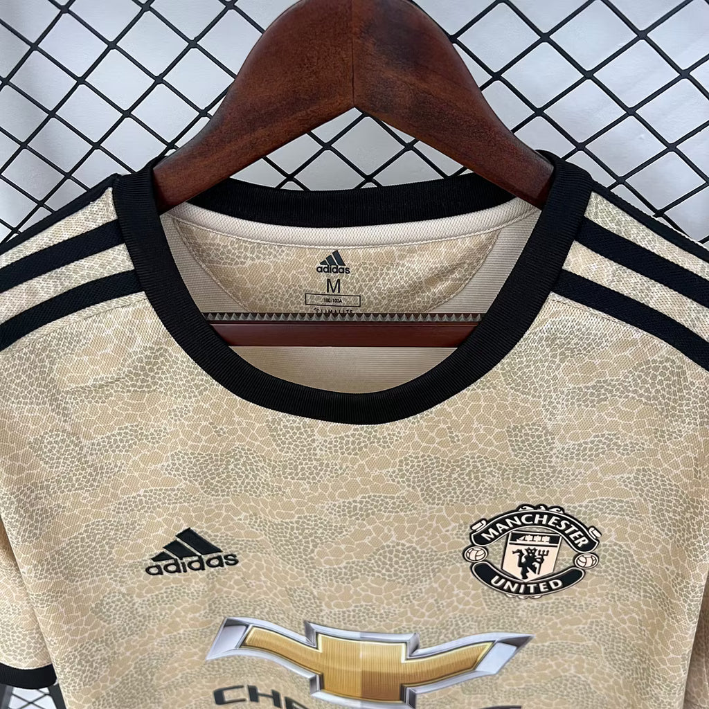Retro football jersey close-up: gold fabric, black collar, adidas logo and crest