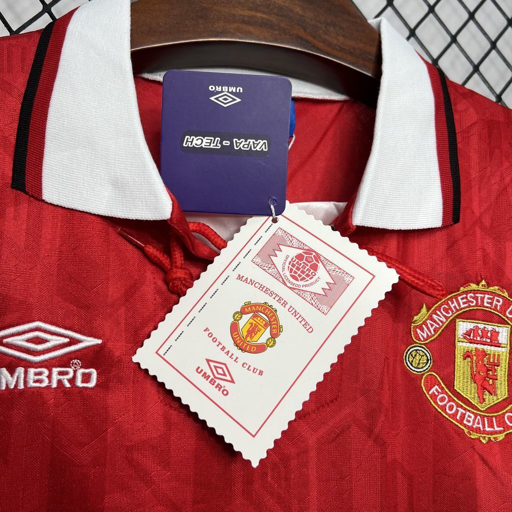 Red football jersey collar with white trim, inside label, and Manchester United crest patch