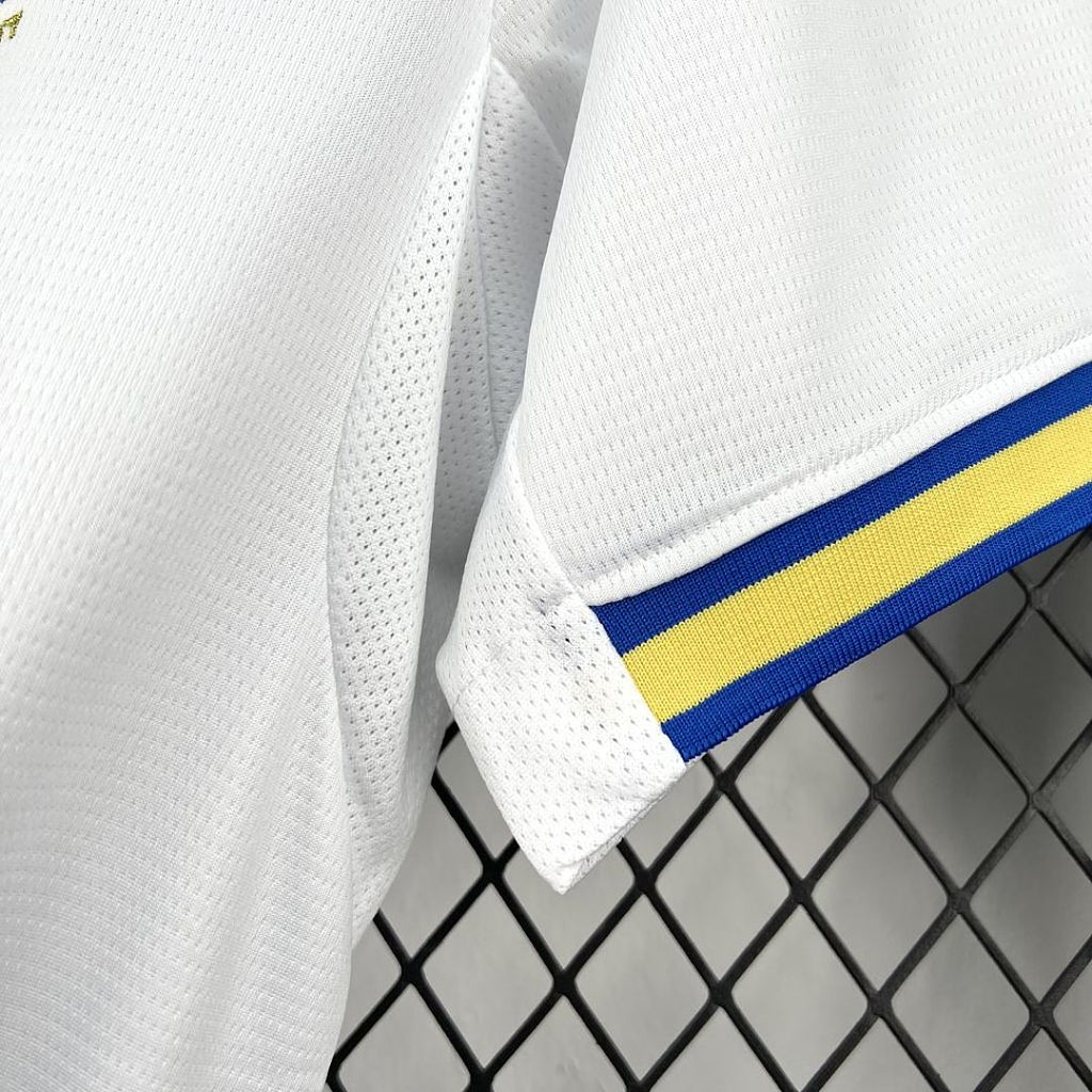 White football jersey sleeve with blue and yellow stripe detail at cuff