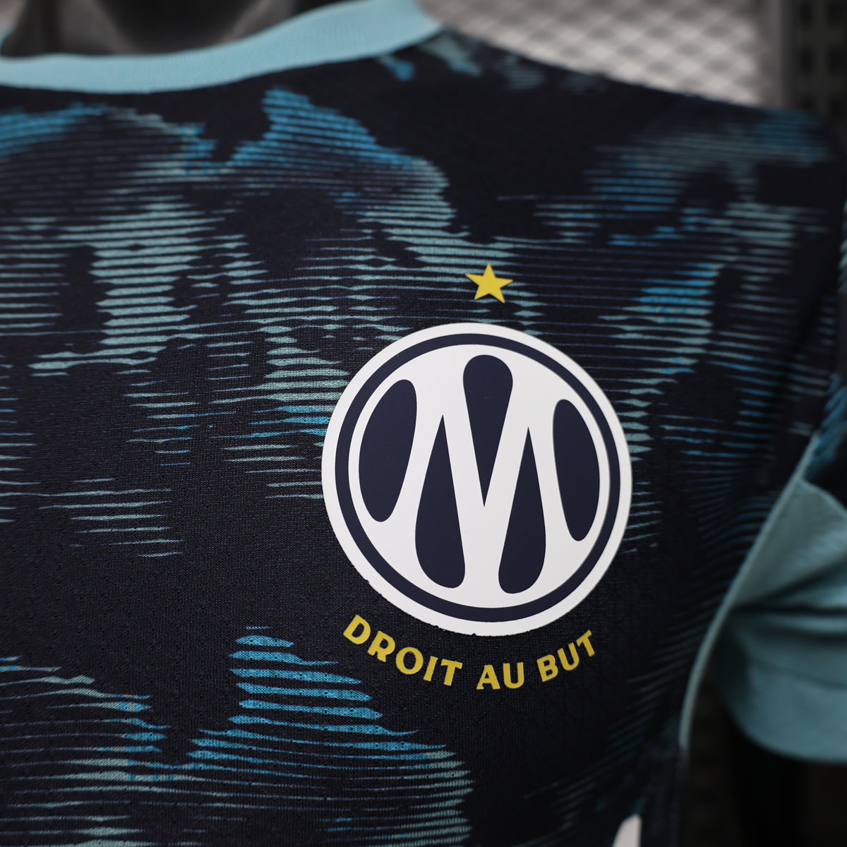 Dark navy soccer jersey showing circular club crest with yellow star and 'DROIT AU BUT' text.