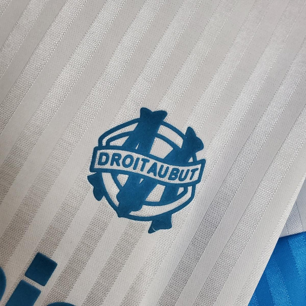 White jersey fabric with blue DROTAUBUT crest on vertical stripe texture
