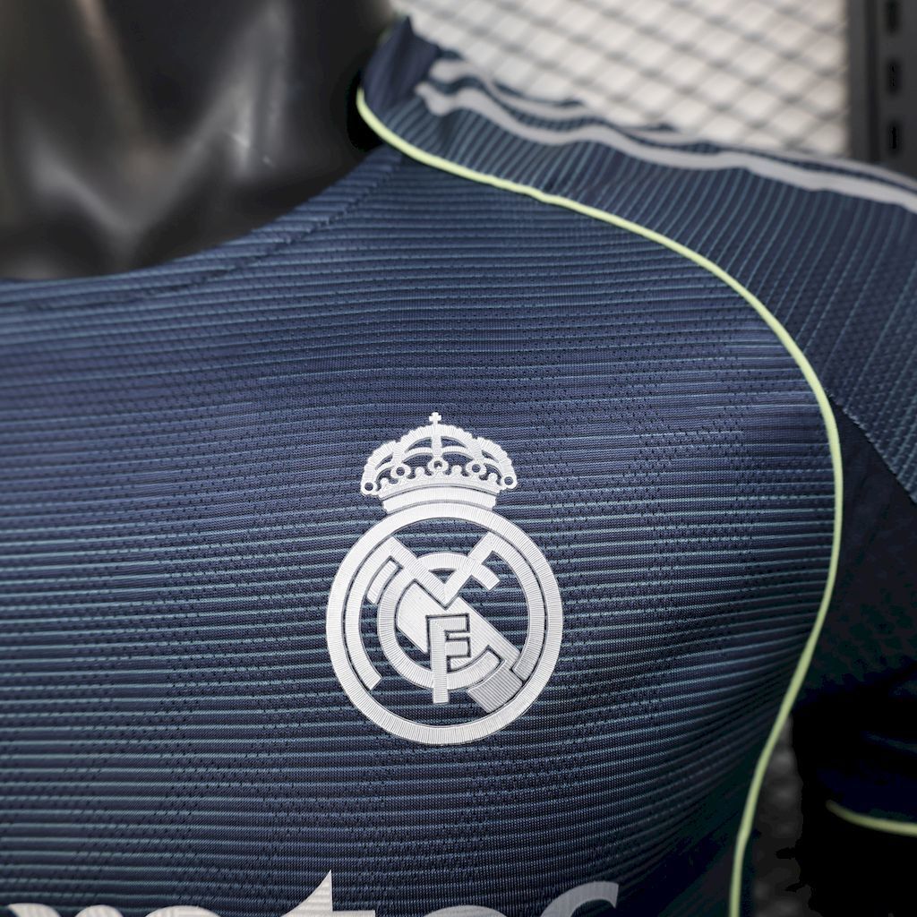 Real Madrid crest on navy soccer jersey with neon edge piping