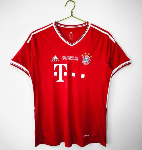Red Bayern Munich home football jersey on hanger with white V-neck trim and crest