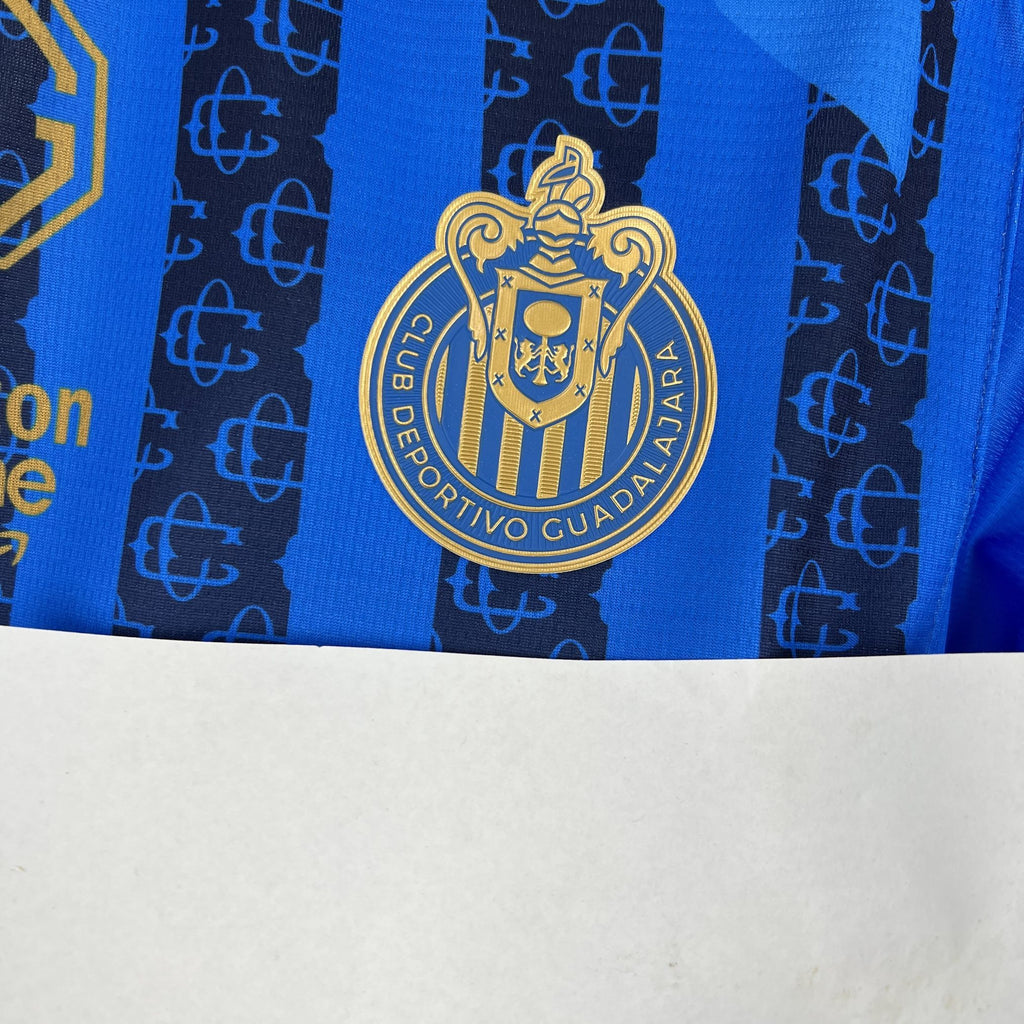 Blue soccer jersey with large gold crest at center on vertical stripe pattern