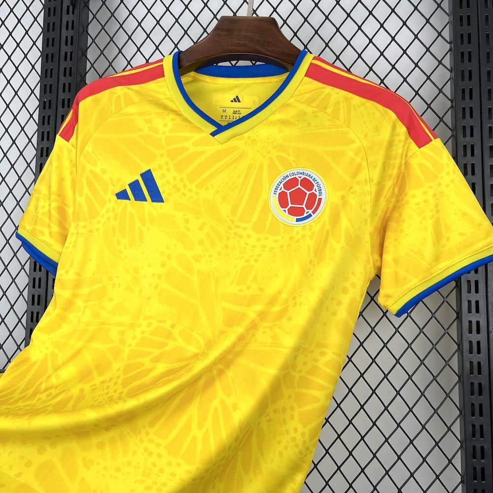 Yellow Colombia home soccer jersey front, blue collar, chest crest, red shoulder accents.