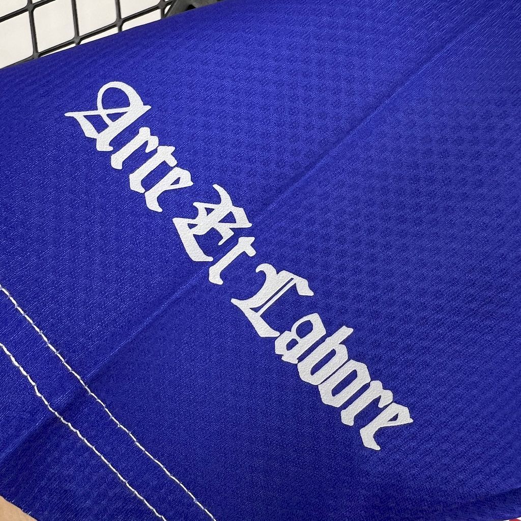 Close-up of retro football shirt sleeve with “Arto Labore” text and blue woven fabric