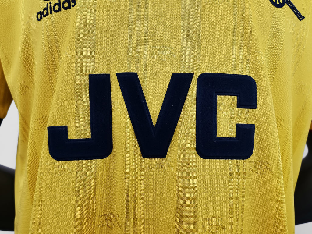 Yellow retro football jersey close-up showing large navy JVC lettering