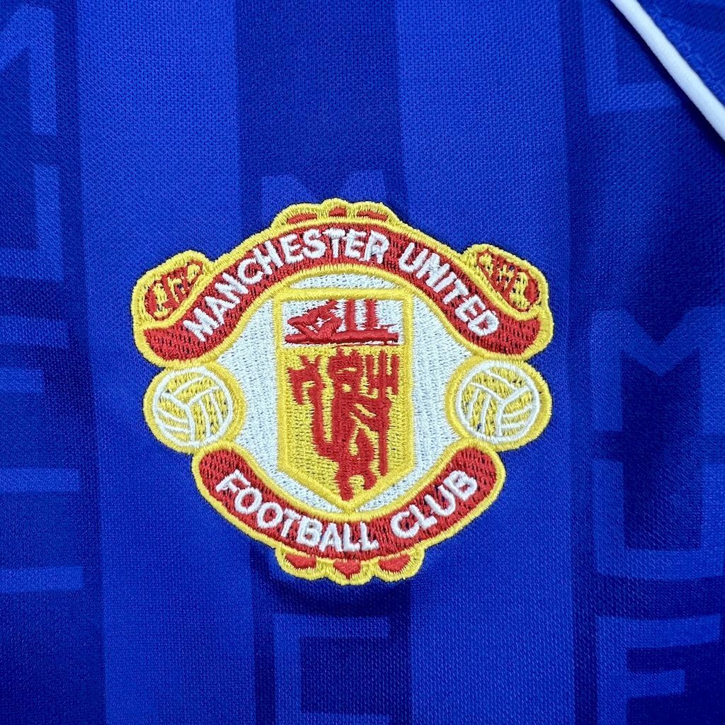 Manchester United crest patch on blue retro football shirt