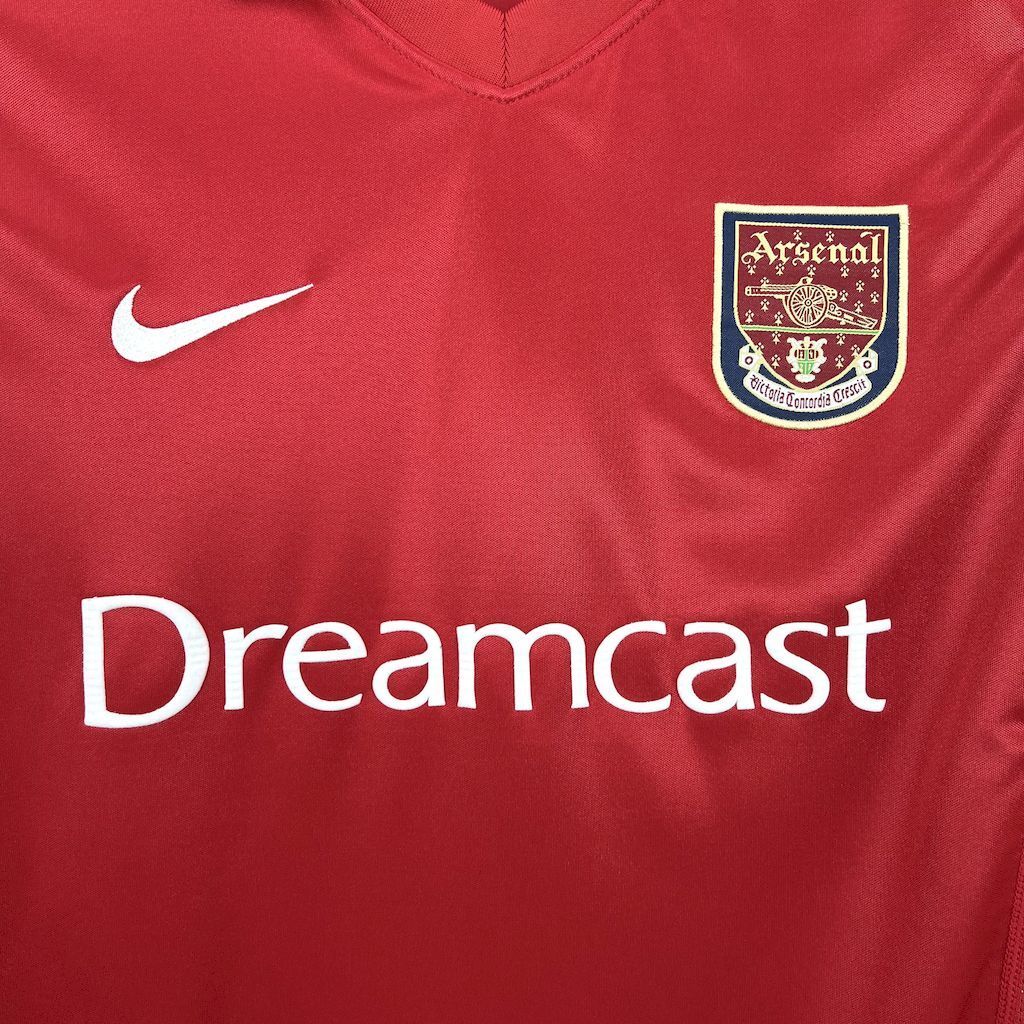 Red retro soccer jersey close-up showing Dreamcast sponsor and Arsenal crest