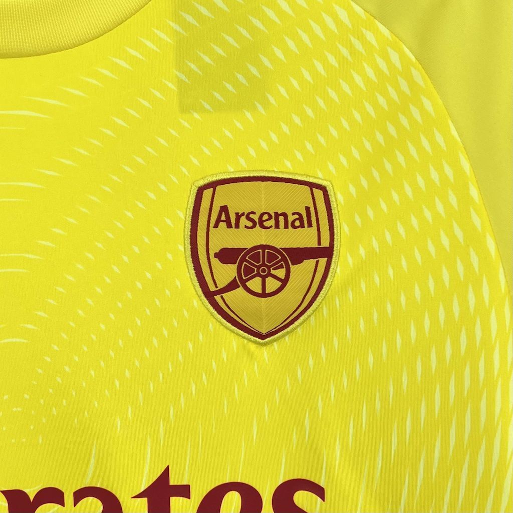 Neon yellow goalkeeper jersey with Arsenal crest badge and patterned fabric texture