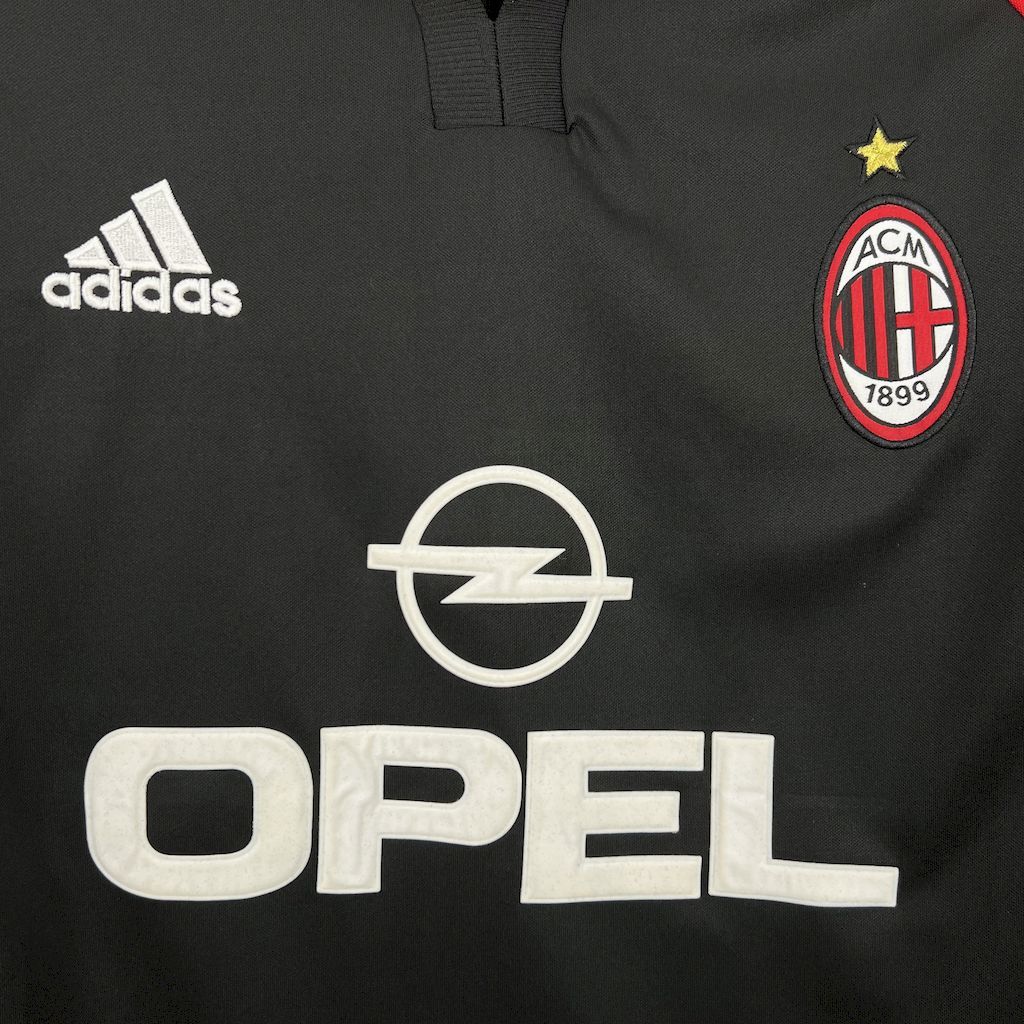 Black soccer jersey close-up with adidas logo, AC Milan crest, and Opel sponsor