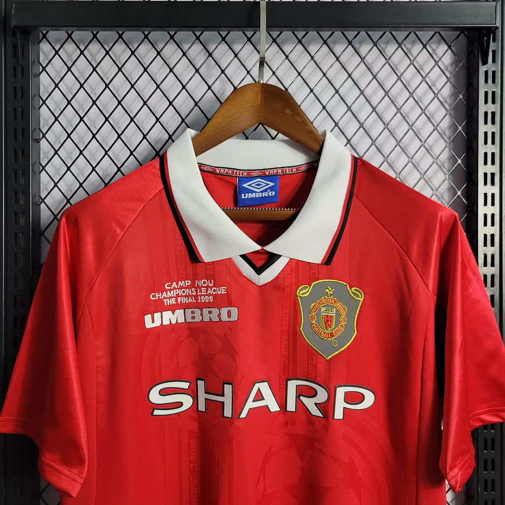 Red Manchester United jersey close-up with crest, Sharp sponsor, and Umbro logo
