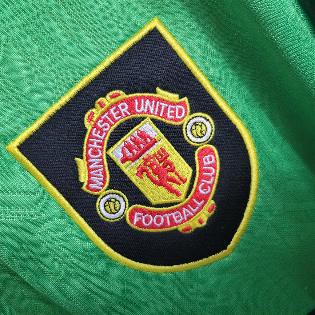 Embroidered club crest patch on green football jersey with yellow border