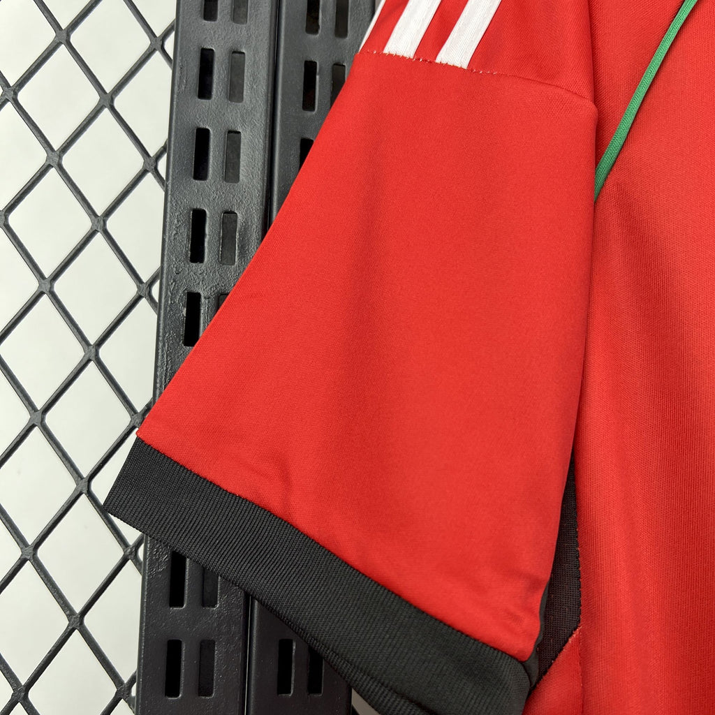Red soccer jersey shoulder with green accent stripe and black hem trim