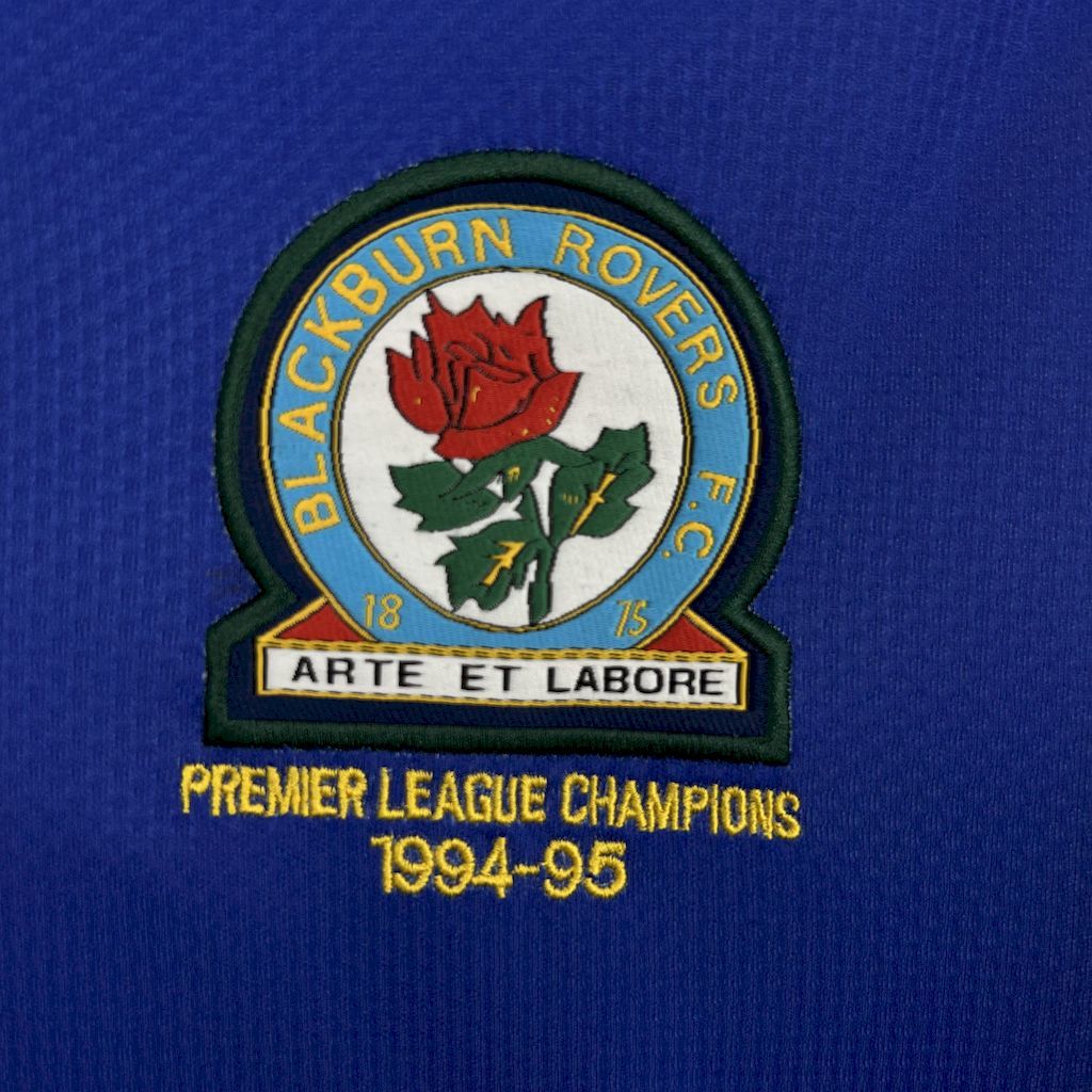 Retro home football shirt crest patch on blue fabric with “Arte Et Labore” ribbon