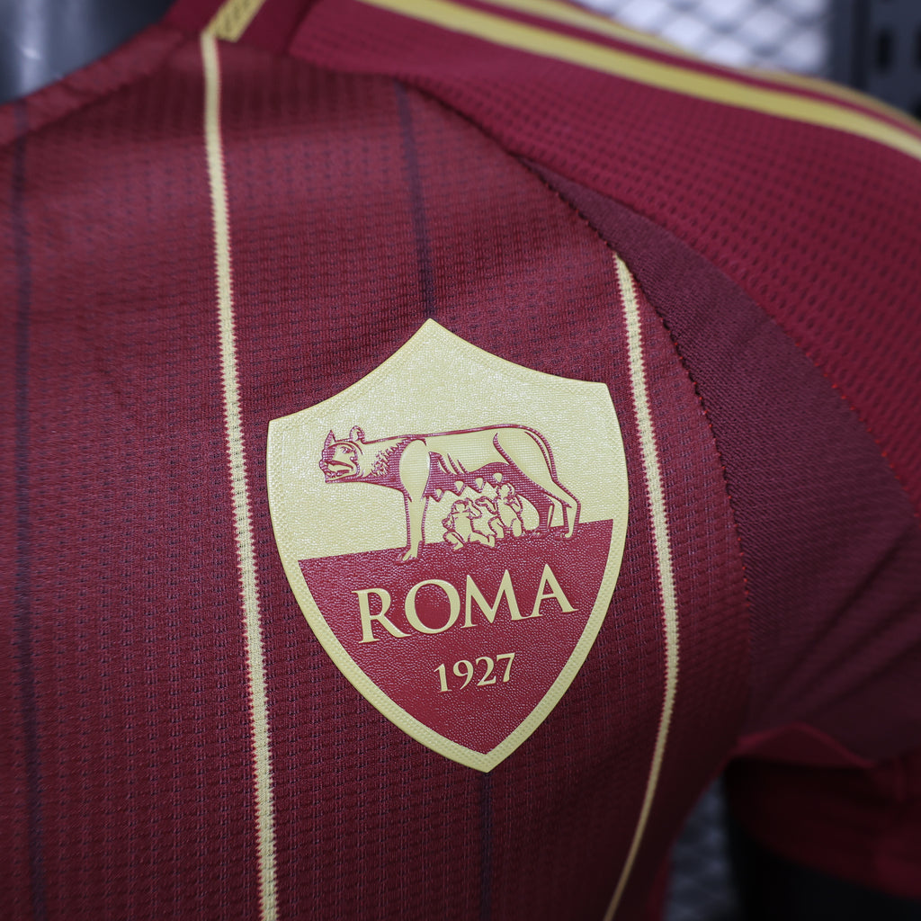 Maroon Roma crest shield on jersey with “ROMA 1927” text