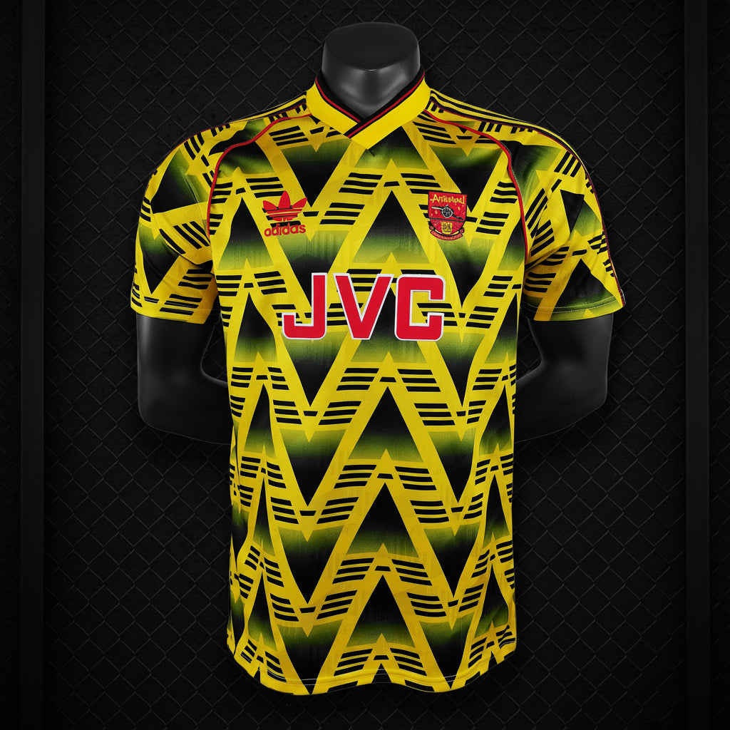 Yellow retro football jersey with black zigzag pattern, red JVC sponsor, and Arsenal crest