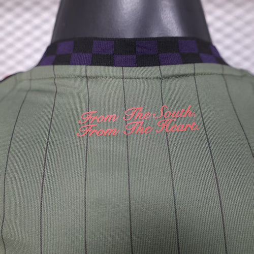 Close-up of green jersey collar with purple check pattern and red script text