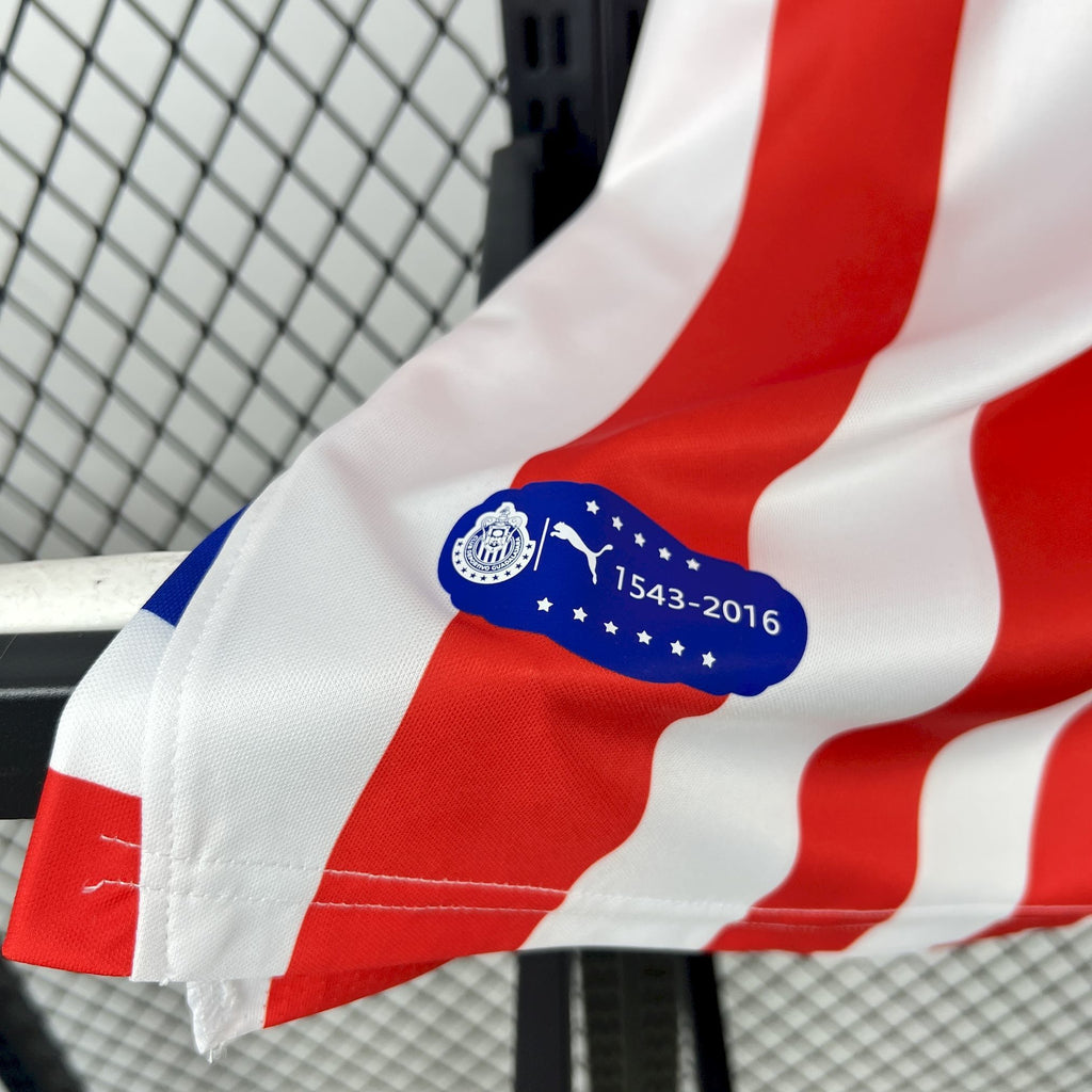 Retro soccer jersey sleeve close-up with blue emblem and red-and-white stripe pattern.