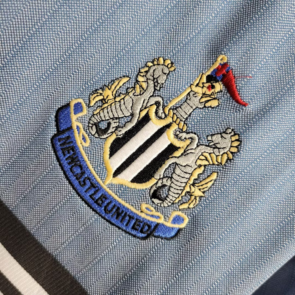 Embroidered circular club badge on light blue fabric with woven texture