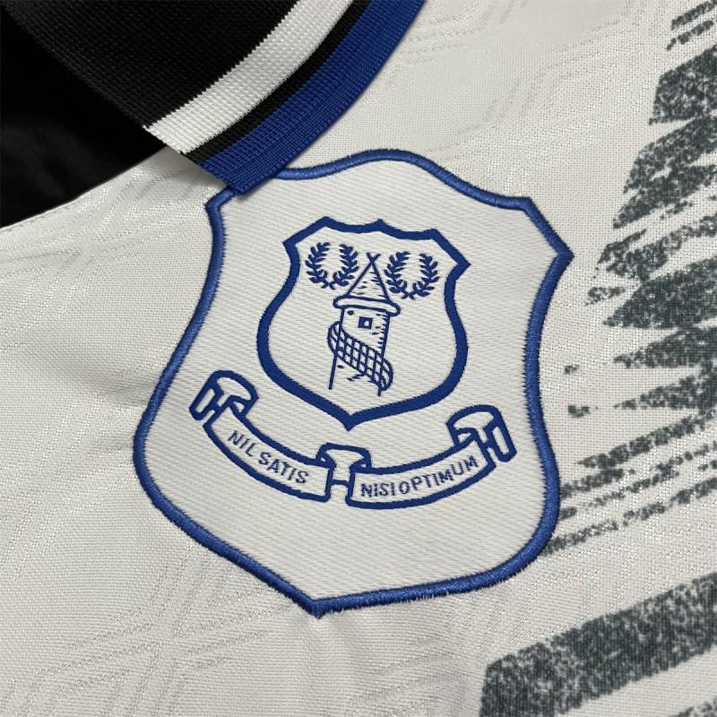 Everton crest badge on retro away jersey, blue outline over white fabric with black print