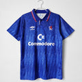 Blue retro football jersey with red/white collar trim and commodore sponsor logo