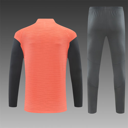 Orange quarter-zip training top with dark gray track pants, rear view
