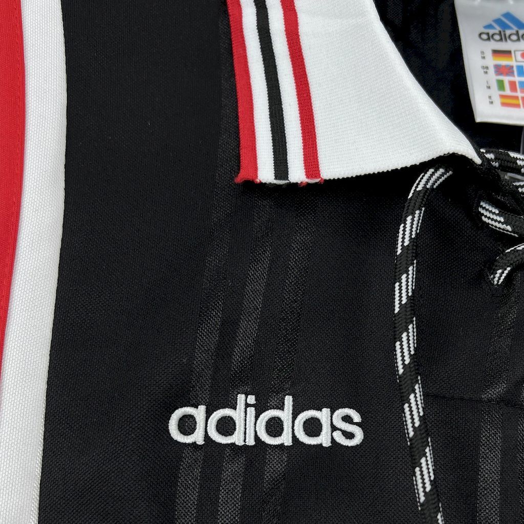 Black jersey front with adidas logo and white-red stripe detail near collar
